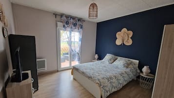 A bedroom with a bed, a TV, a window with curtains, and a door.