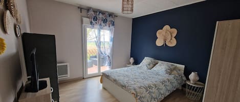 Une chambre à coucher avec un lit, une télévision, une fenêtre avec des rideaux et une porte.