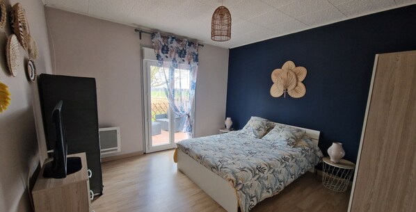 A bedroom with a bed, a TV, a window with curtains, and a door.