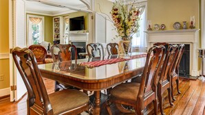 A formal dining room with a large wooden table, ornate chairs, a chandelier, and a fireplace. - Historic Charm, Prime Location Steps to River St & Parking (Savannah)