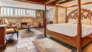 Ein geräumiges Schlafzimmer mit Himmelbett, Steinwand und großem Fenster.
