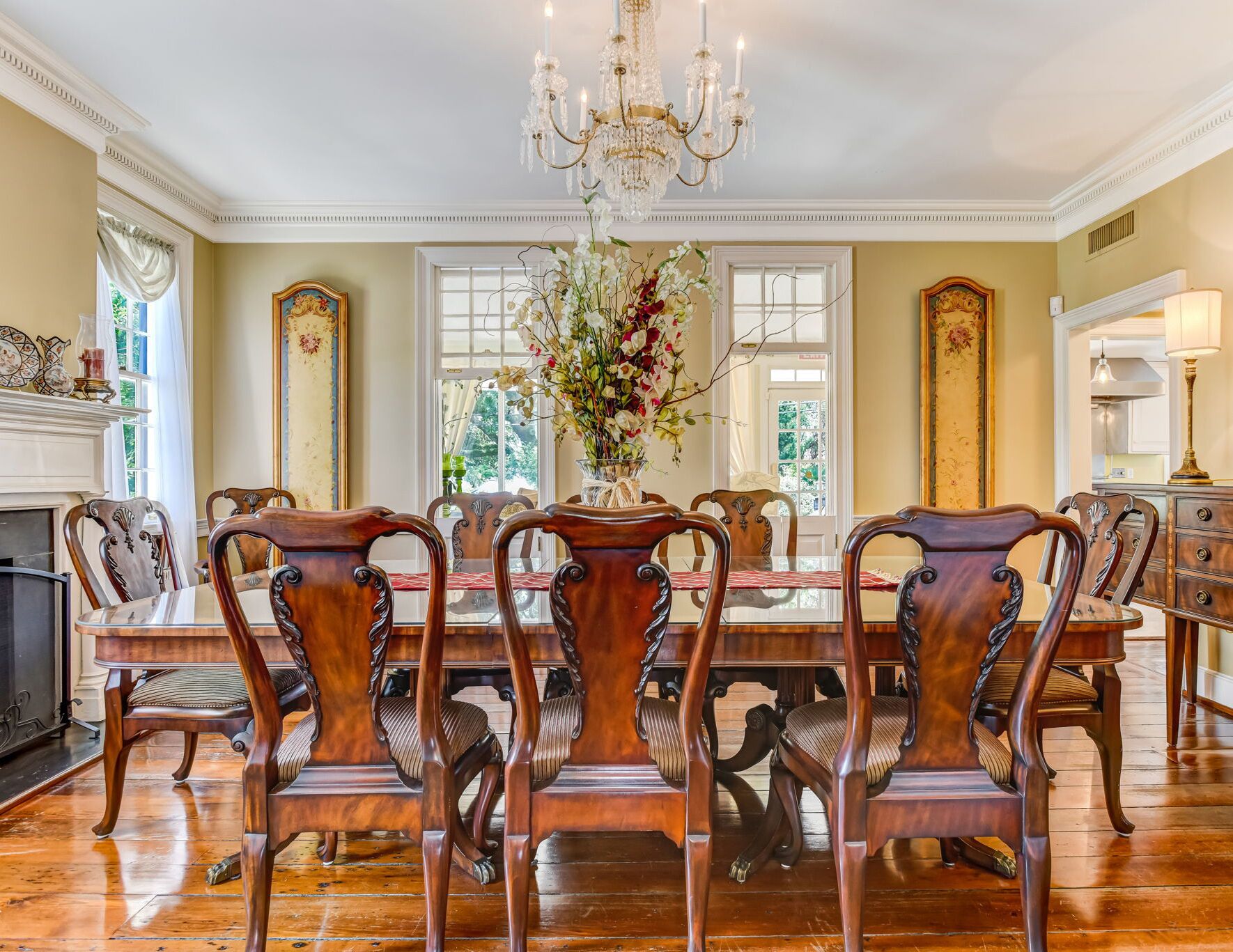 A formal dining room with a large wooden table, six chairs, and a chandelier.