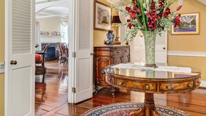 Ein gut beleuchteter Flur mit Holzboden, einem runden Tisch mit Blumenvase und einer Treppe mit Geländer.