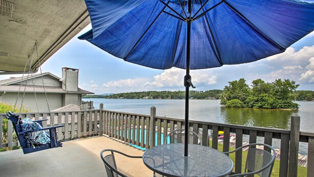A balcony with a table and chairs, overlooking a lake with a wooden deck and a boat dock. - Balcony & Lake Access: Hot Springs Getaway! (Hot Springs)