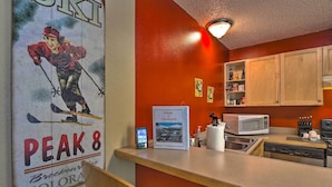A kitchen with wooden cabinets, a microwave, and a dishwasher. - Ski & Unwind Fireside: Main St Condo in Tannhauser (Breckenridge)