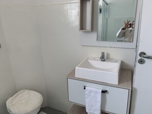 A bathroom with a white sink, a mirror above it, and a towel hanging on a rack. - Comfortable apartment near Hospital das Clínicas, Allianz Parque, São Camilo, and the subway. (São Paulo)