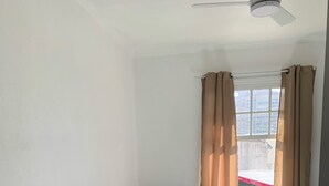 Un dormitorio con dos camas, una mesita de noche de madera y una ventana con cortinas.