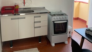 Una cocina compacta con gabinetes blancos, estufa a gas, horno empotrado y un lavamanos pequeño.