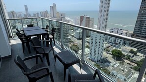 Ein Balkon mit Blick auf das Meer und die Stadt, ausgestattet mit Tisch und Stühlen.