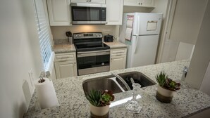 A kitchen with white cabinets, a stainless steel stove, a microwave, and a refrigerator. - Close to Attractions, Sleeps 4 (Orlando)
