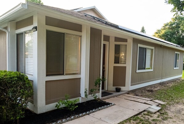 A single-story house with a covered porch, large windows, and a small garden area.