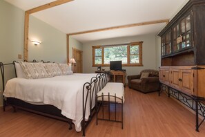 A bedroom with a bed, a wooden cabinet, a chair, and a window.