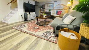 A living room with a sofa, coffee table, and a television. There is a staircase leading to another level. - Your Comfy Home in Pittsburgh with King beds and free parking (Pittsburgh)