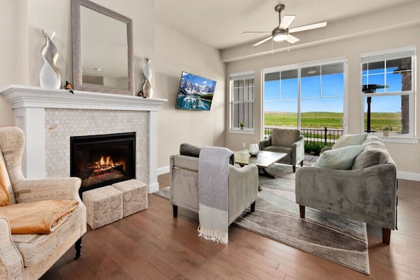 A living room with a fireplace, a sofa, a coffee table, and a view of the outdoors.