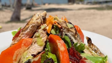 A grilled chicken sandwich with lettuce and tomato on a white plate.