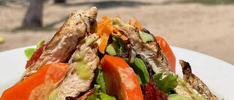 A grilled chicken sandwich with lettuce and tomato on a white plate.