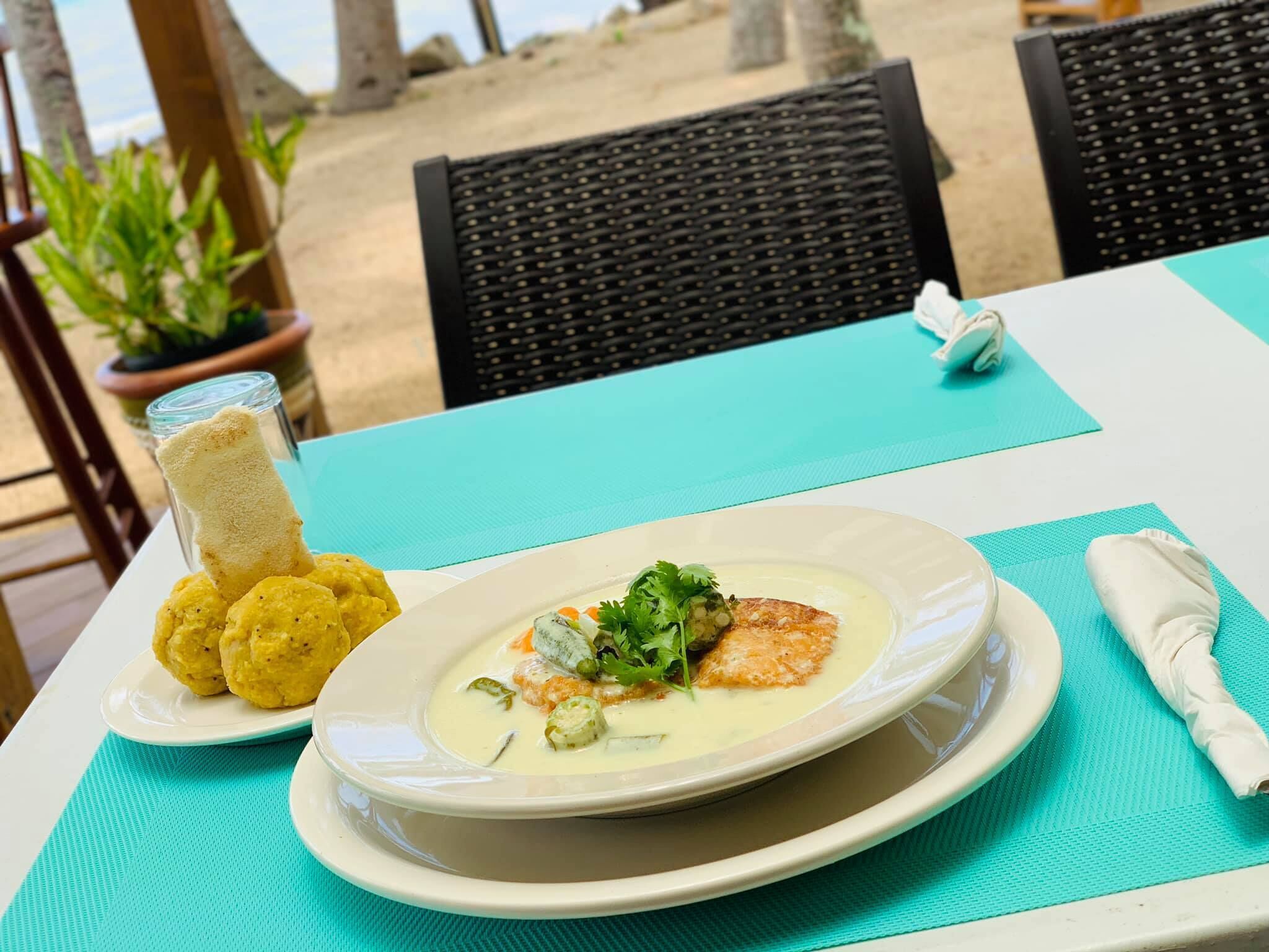 A table with a plate of food, a glass of a beverage, and a napkin on a turquoise tablecloth.