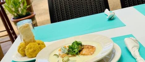 A table with a plate of food, a glass of a beverage, and a napkin on a turquoise tablecloth.