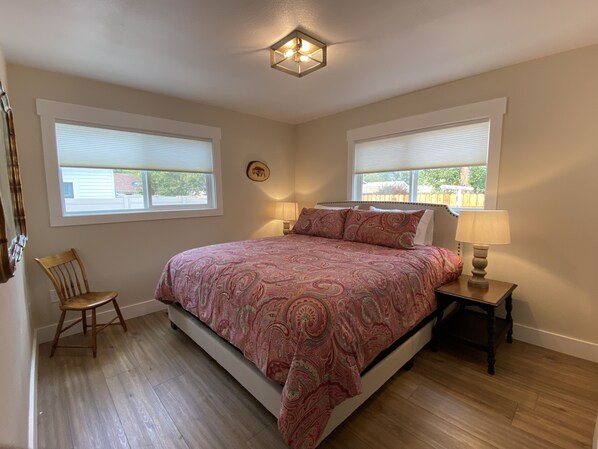 Ein Schlafzimmer mit einem großen Bett, zwei Nachttischlampen, einem Sessel und einer Deckenleuchte.