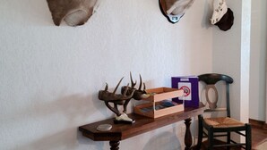 Una habitación con dos venados montados en la pared, una mesa de madera con astas, un cráneo y una caja.