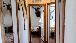 Un pasillo con pisos y paredes de madera, flanqueado por puertas que dan a dormitorios.