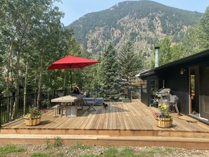 A wooden deck with outdoor furniture, a red umbrella, and a mountain backdrop. - Large house in the mountains, (pre-approved!) dogs welcome  (Georgetown)