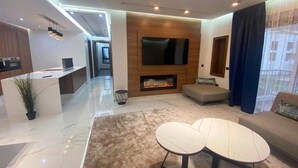 A modern living room with a flat-screen TV, a fireplace, a sofa, and a dining area with a table. - Residence Marina Agadir 5428 (Agadir)