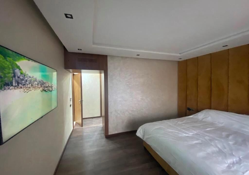 Un dormitorio moderno con una cama grande, un cuadro en la pared y una puerta que da a otra habitación.
