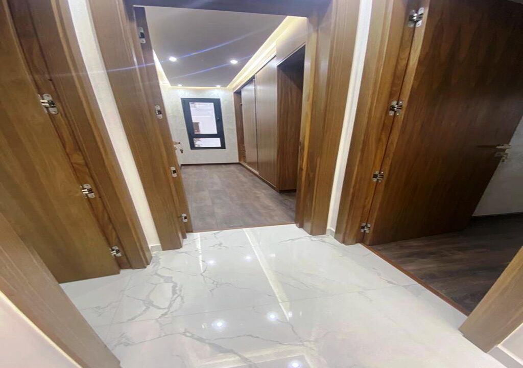 A hallway with wooden doors and a marble floor.