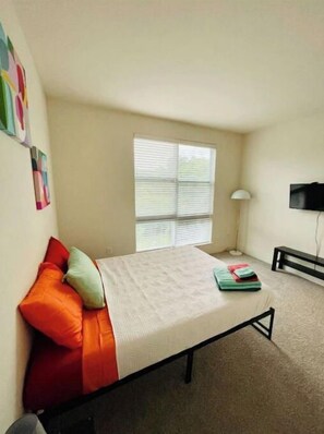 Cozy retreat with a bed, flat-screen TV, and a small table near the window.