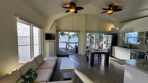 A spacious living area with a sofa, dining table, and kitchen. It features large windows and a view of the ocean.