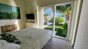 A bedroom with a large bed, a TV, and a view of a garden through a sliding door.