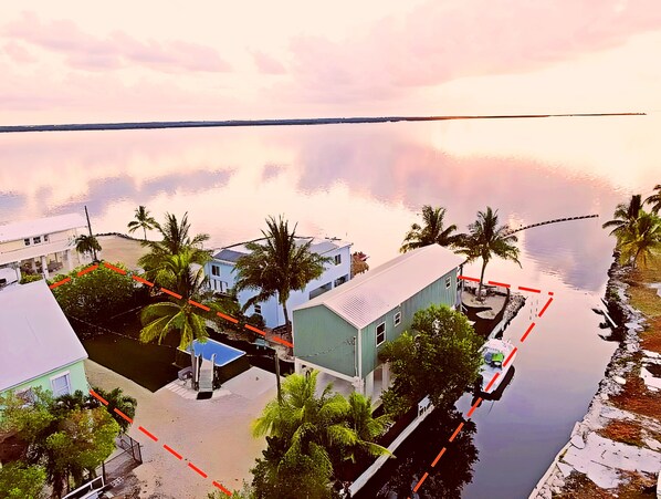 Zona residencial costera con casas, palmeras y una masa de agua tranquila.