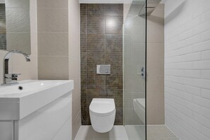 Un baño moderno con un lavabo blanco, cabina de ducha de vidrio y un inodoro.