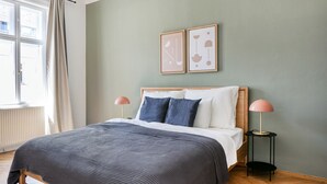 Une chambre à coucher avec un lit, deux lampes de chevet, un radiateur et deux tableaux encadrés accrochés au mur.