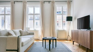 Un salon avec un canapé, une table basse, un téléviseur posé sur un meuble en bois et une lampe sur pied.