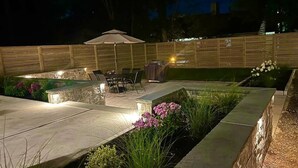 An outdoor patio area with a seating arrangement, a barbecue grill, and a decorative fence.