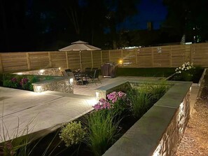 An outdoor patio area with a seating arrangement, a barbecue grill, and a decorative fence.