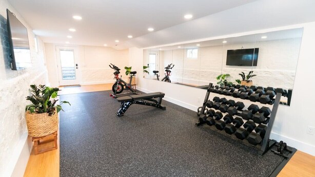 A modern gym with exercise equipment, a bench, and dumbbells.