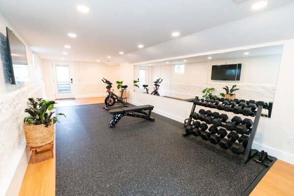 A modern gym with exercise equipment, a bench, and dumbbells.