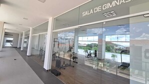 A modern gym with glass walls, a visible ceiling, and a view of the outdoors.