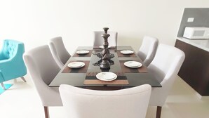 A dining table set for four with white chairs, a decorative centerpiece, and a microwave on a counter to the right.