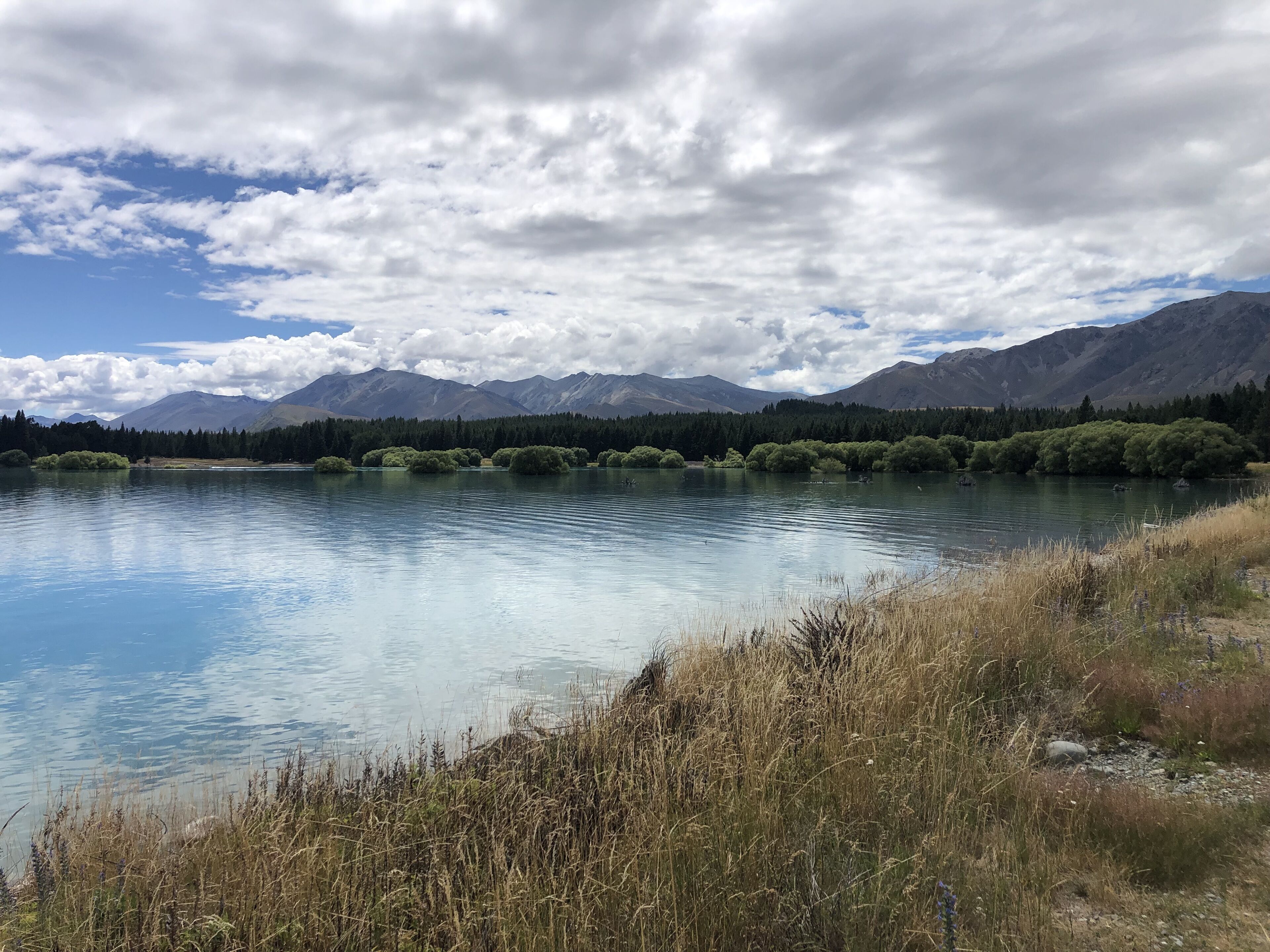 A calm lake with mountains in the background and a clear sky.