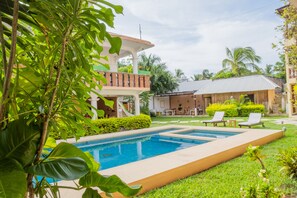 Una piscina al aire libre, sombrillas, sillones reclinables de piscina