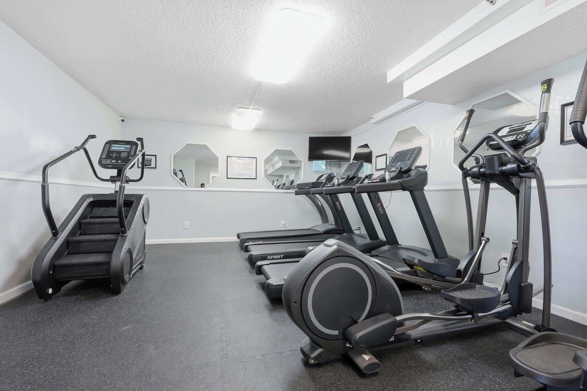 Un gimnasio con cintas de correr, elíptica y escaladora.