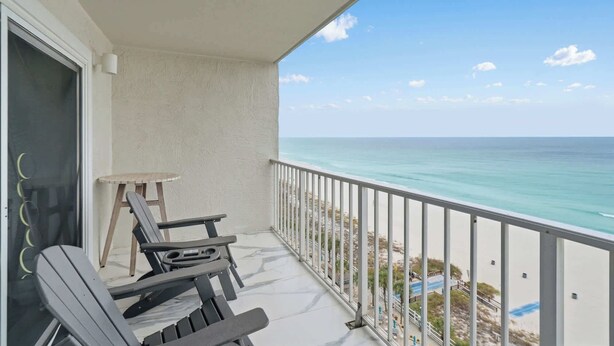Un balcon avec deux fauteuils Adirondack, une petite table et une vue sur l’océan.