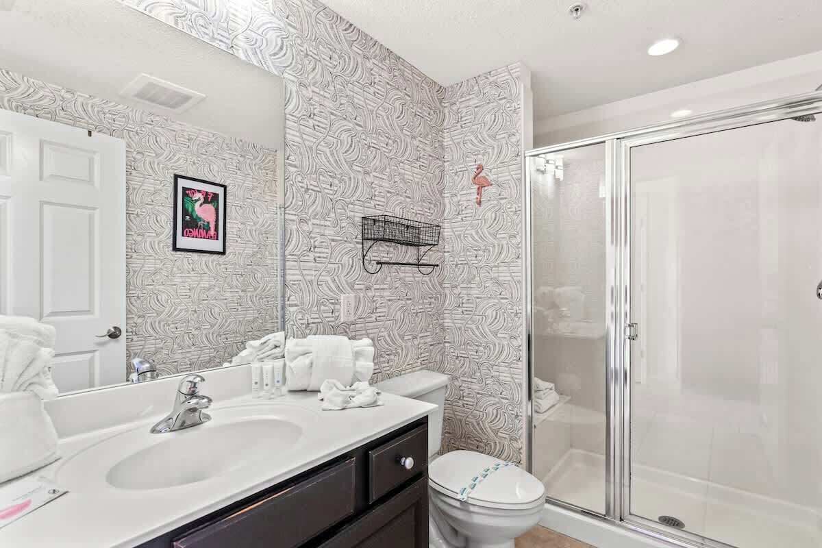 Un bany amb un rentapins blanc, un vàter i una cabina de dutxa de vidre.