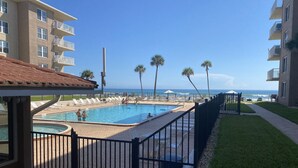 Un área de piscina con varias piscinas, un espacio de descanso techado y vista al océano.