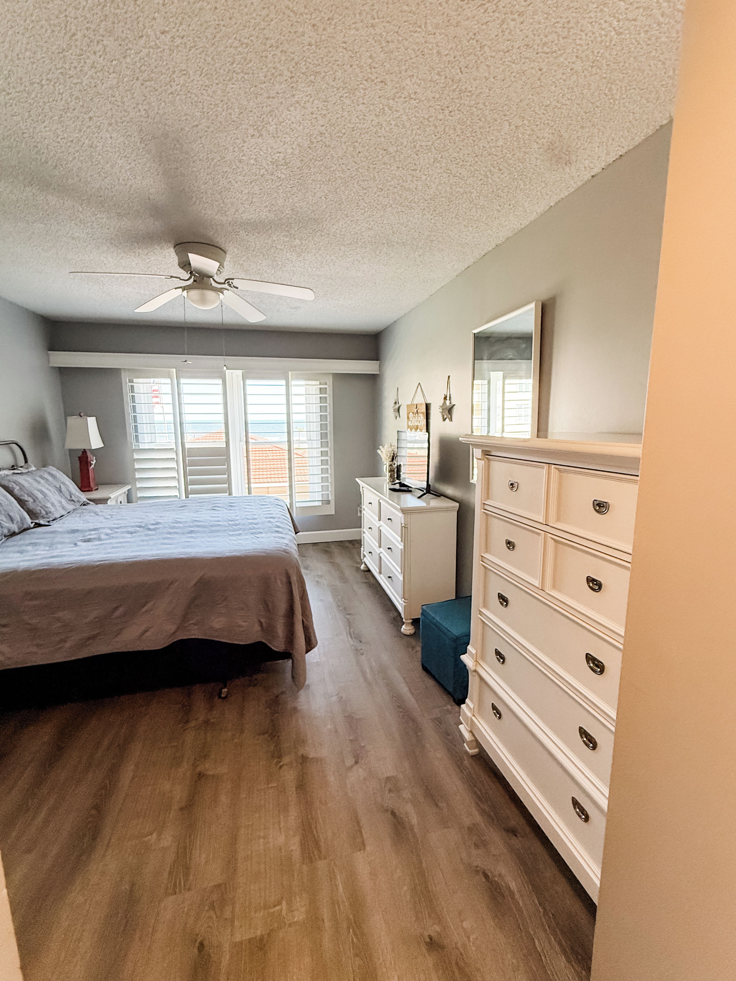 Une chambre à coucher avec un lit, une commode et un ventilateur de plafond.
