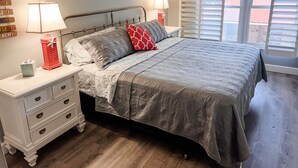 Un dormitorio con cama, mesitas de noche y una ventana con persianas.